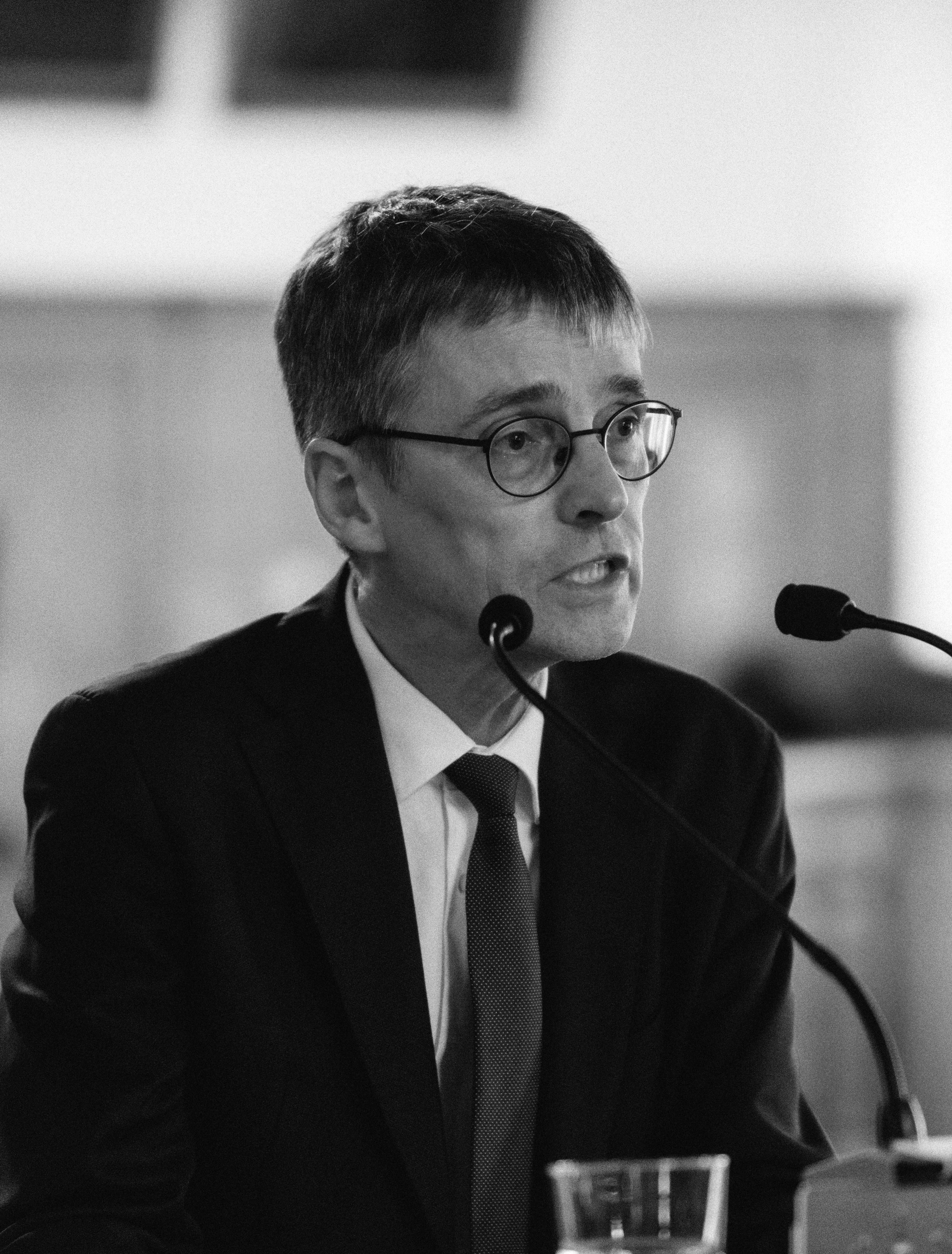 Portraitbild einer männlichen Person an einem Rednerpult