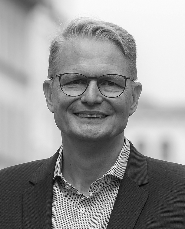 Black-and-white portrait photograph of a smiling man wearing glasses.